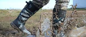 rubber hunting boots splashing through muddy water