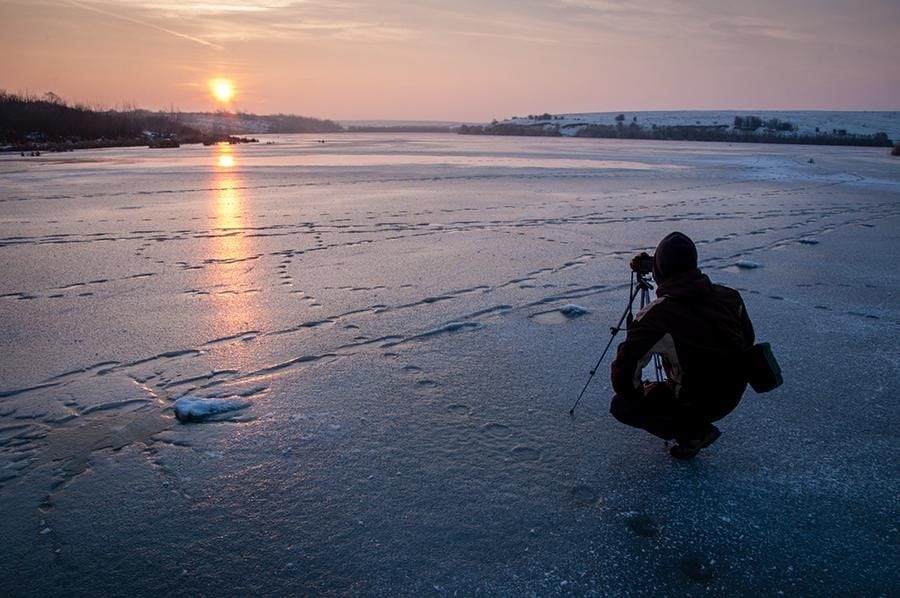 a man with a camera during sunrise on the ice
