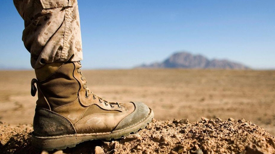 soldier foot with military boot in desert with mountain in distance