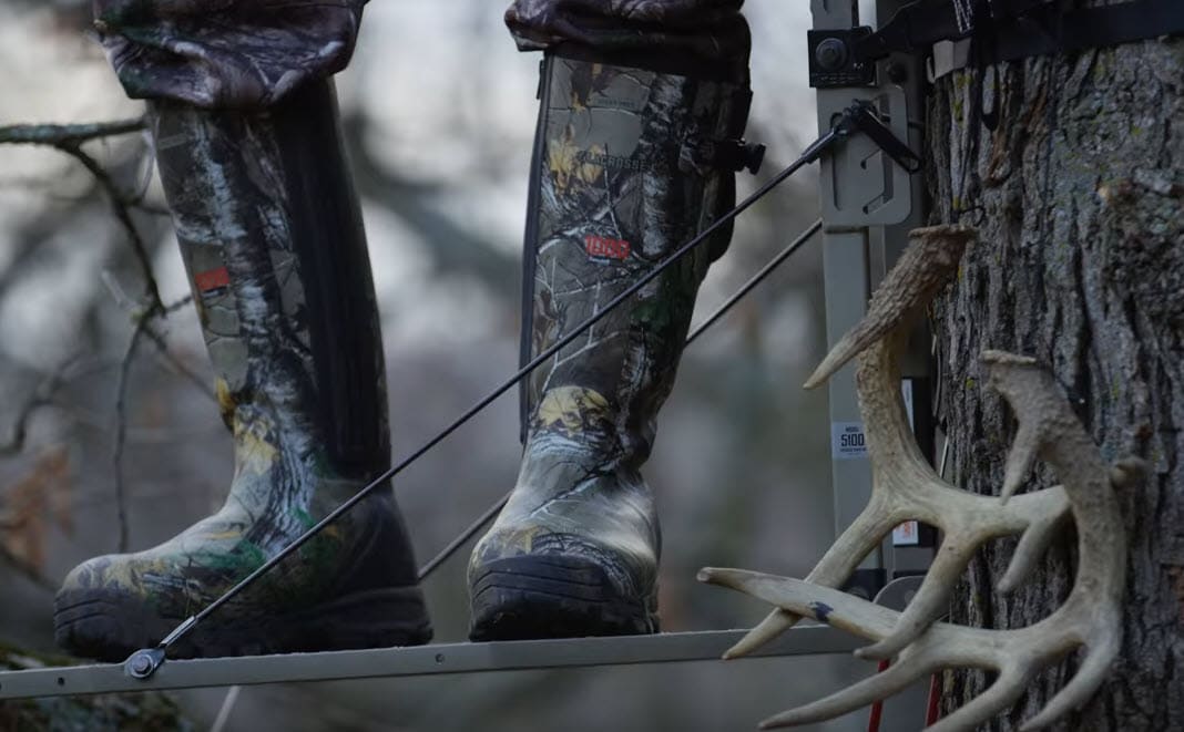 warm rubber hunting boots on feet standing on tree stand